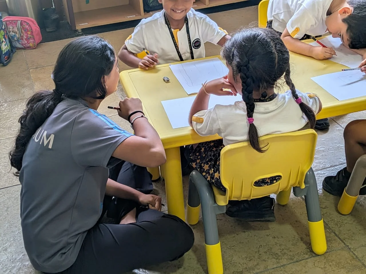 A volunteer supporting primary students with an art activity