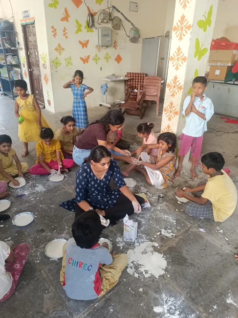 Children and volunteers exploring oobleck while seated together on the floor